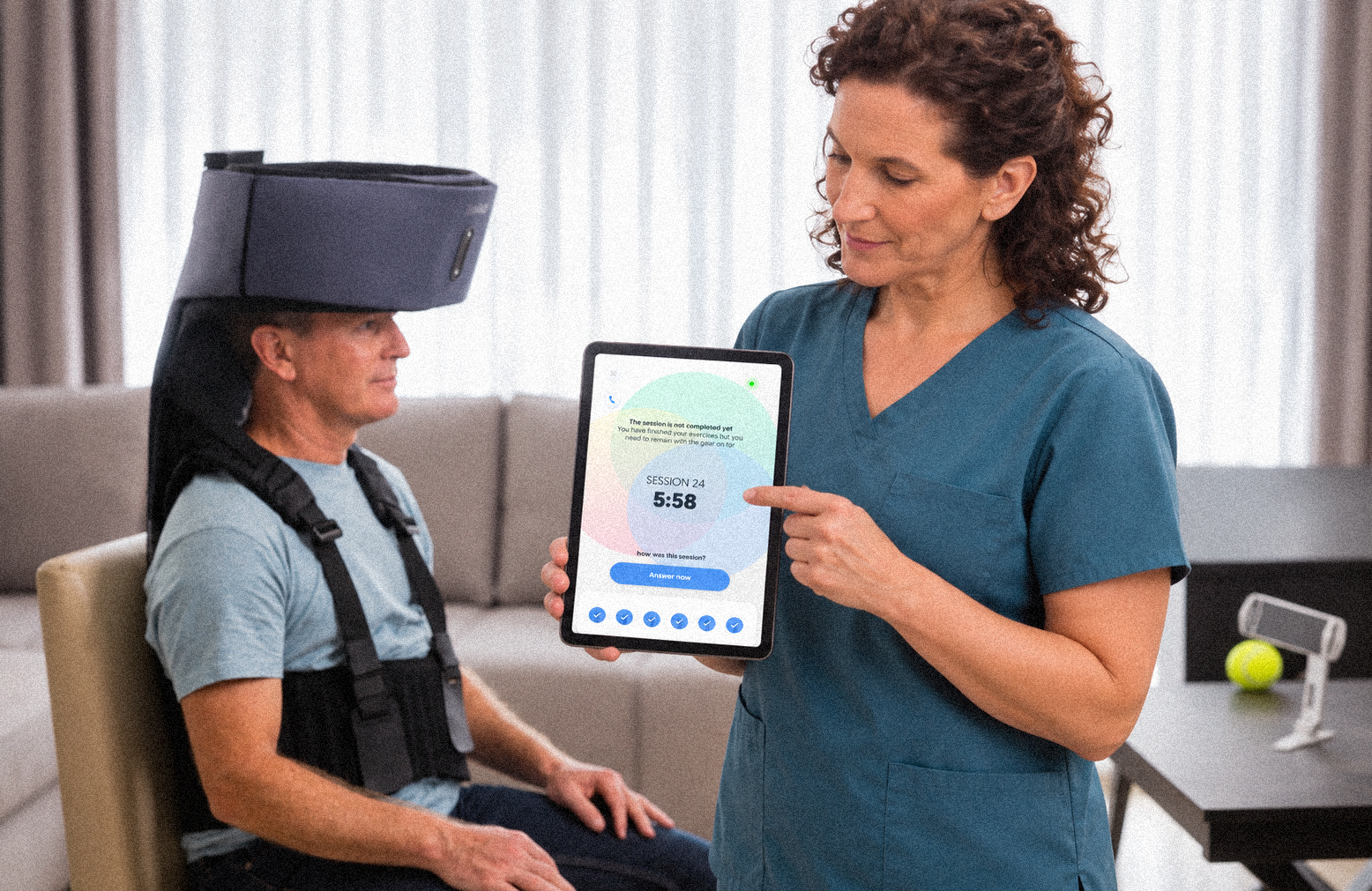 A clinician showing a BrainQ session on a tablet to a patient wearing the BrainQ device